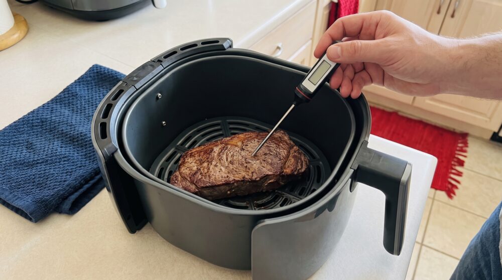 Gebräuntes Steak im geöffneten Airfryer mit Fleischthermometer im dicksten Bereich