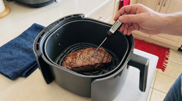Gebräuntes Steak im geöffneten Airfryer mit Fleischthermometer im dicksten Bereich