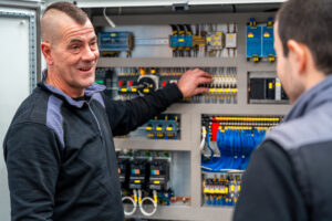 Zwei männliche Industrietechniker bei der Installation und Wartung elektrischer und mechanischer Systeme in einer Fabrik als Symbolbild für Ratgeber: Job Shadowing