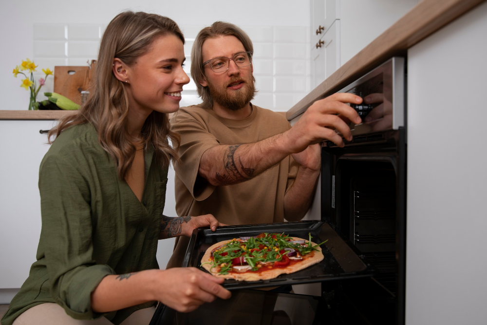 Zwei Personen schieben gemeinsam eine belegte Pizza in den Backofen