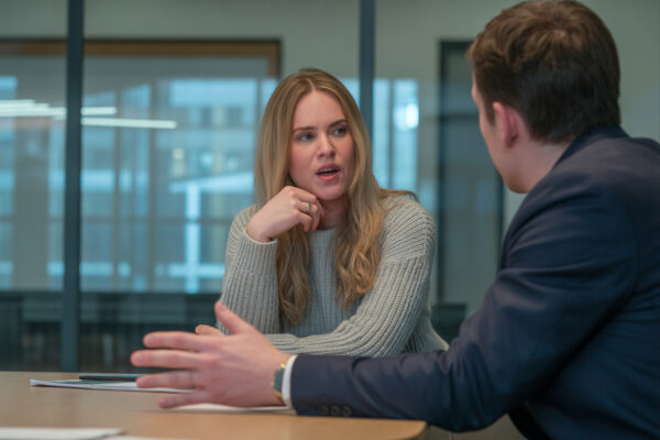 Zwei Personen führen ein unangenehmes Gespräch im Job am Tisch, mit Notizen und ruhiger, konzentrierter Körpersprache.