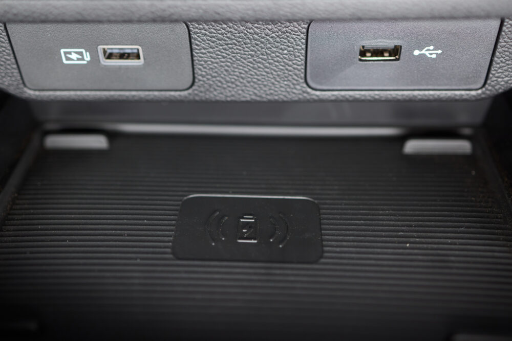 Zwei USB-Anschlüsse sitzen nebeneinander in einer strukturierten Verkleidung über einer Ablage mit Ladesymbol.