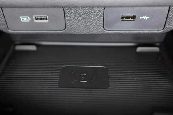 Zwei USB-Anschlüsse sitzen nebeneinander in einer strukturierten Verkleidung über einer Ablage mit Ladesymbol.
