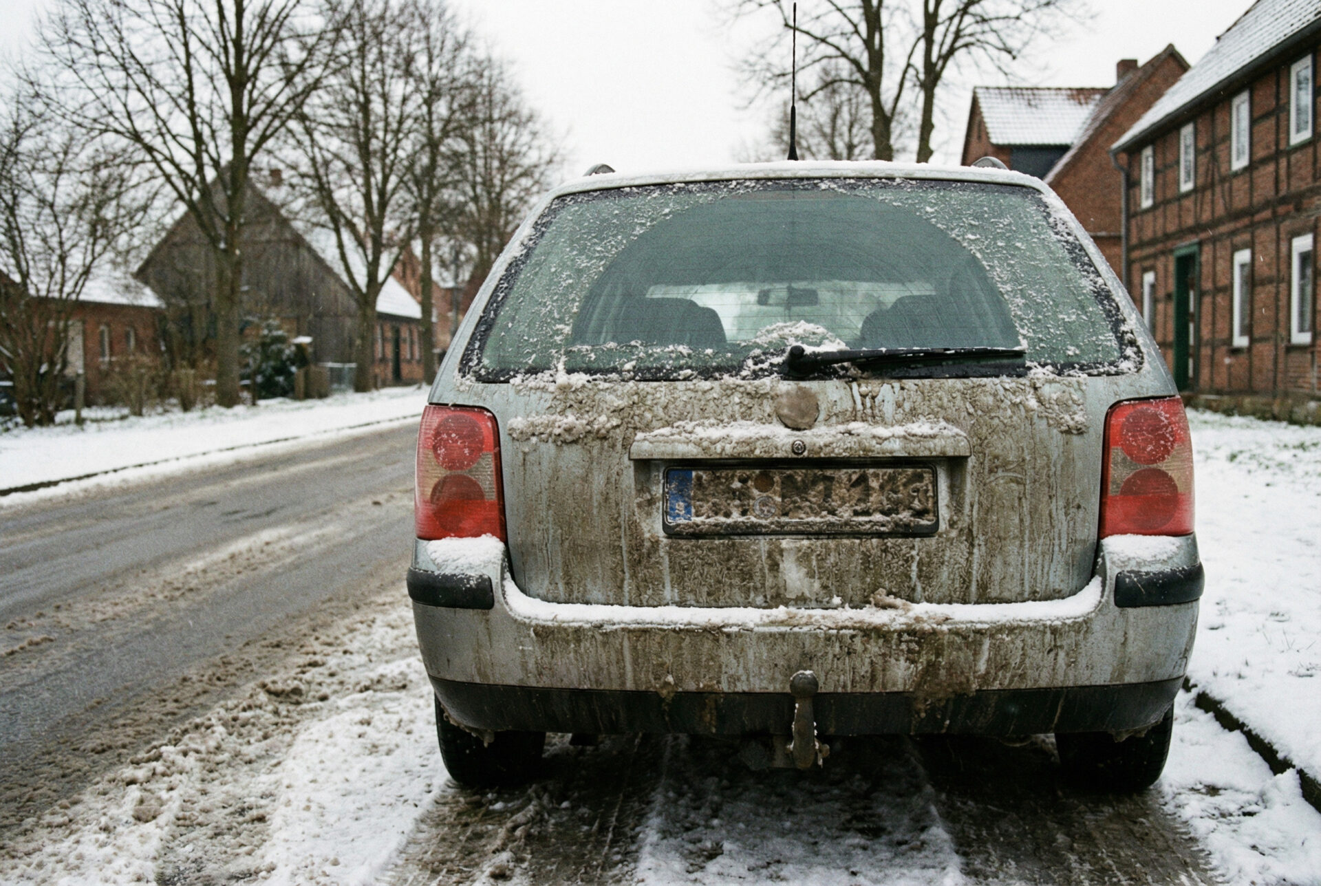 Verschmutztes Kennzeichen im Winter: Auto-Heck mit Schneematsch, Salz und Dreck, Nummernschild kaum lesbar