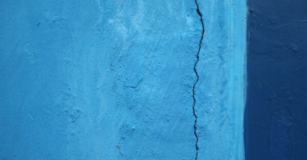 Vertikaler Riss in einer blau gestrichenen Putzwand