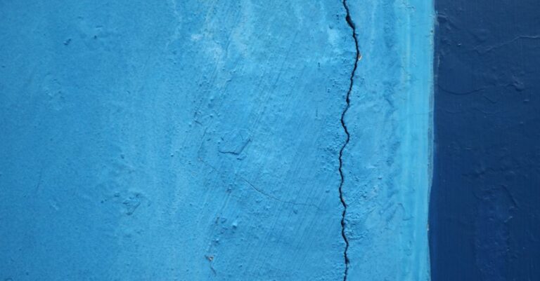 Vertikaler Riss in einer blau gestrichenen Putzwand