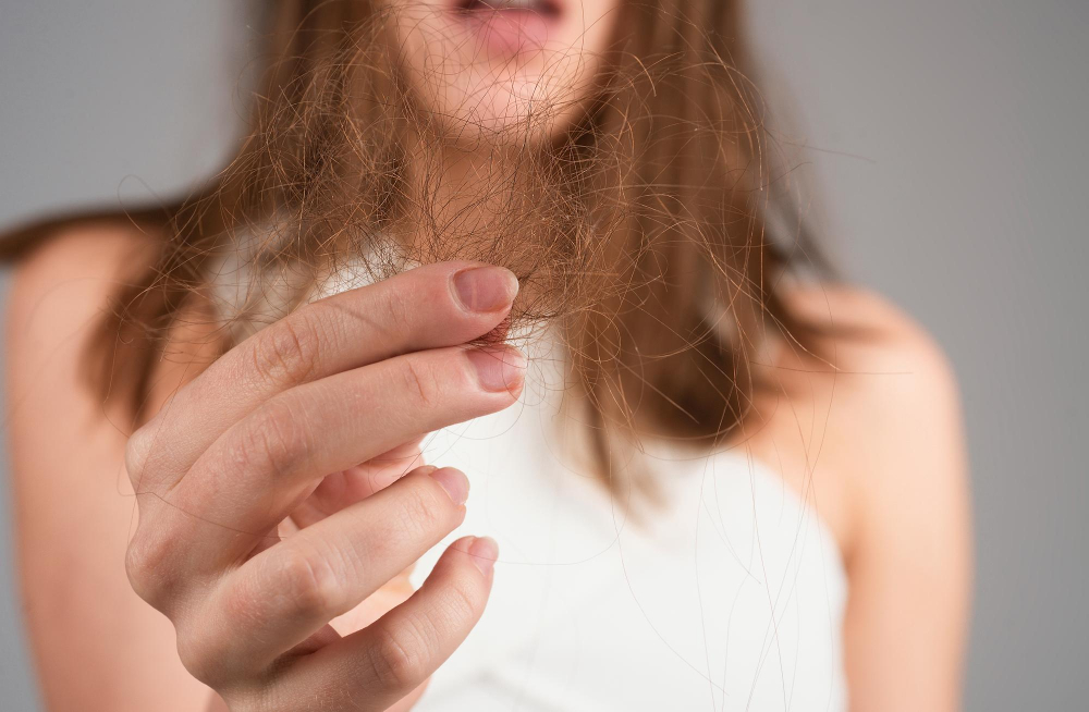 Eine Frau hält eine Haarsträhne in der Hand, symbolisch für das Thema: Was hilft bei Haarausfall bei Frauen?