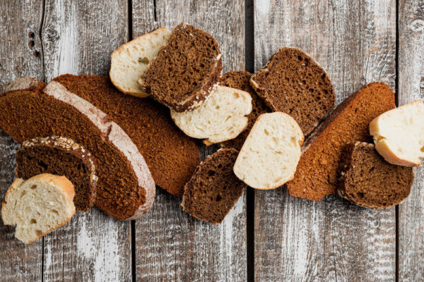 Gemischte, trockene Brotscheiben auf rustikalem Holztisch; zeigt altbackenes Brot zum Verwerten statt Wegwerfen.