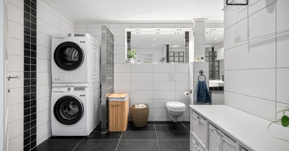 Sleek and modern bathroom with integrated laundry, tiled walls and floor, and stylish decor.