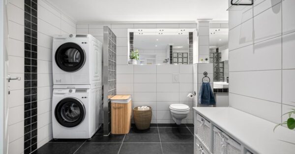 Sleek and modern bathroom with integrated laundry, tiled walls and floor, and stylish decor.