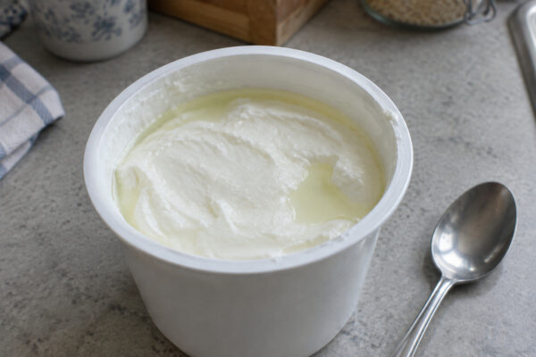 Geöffneter Joghurt mit abgesetzter Flüssigkeit auf der Oberfläche