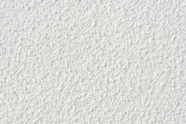 Nahaufnahme einer weißen Wand mit grober, unregelmäßiger Struktur und vielen kleinen Erhebungen und Vertiefungen.