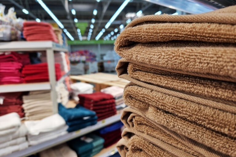 Handtücher liegen gefaltet in einem Geschäft auf verschiedenen Regalstapeln