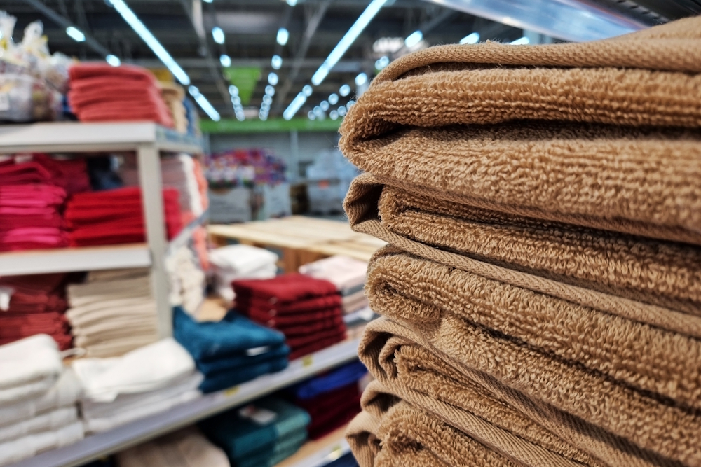 Handtücher liegen gefaltet in einem Geschäft auf verschiedenen Regalstapeln